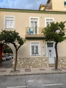 two trees in front of a building with a balcony at Casa El Capitán in Málaga