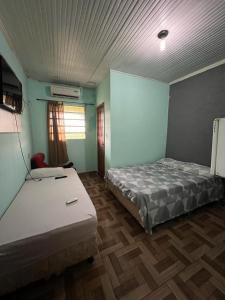 Habitación con 2 camas, paredes azules y suelo de madera. en Hotel Shalon en Rio Branco