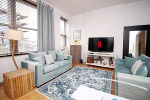 a living room with two blue couches and a tv at Seaside town apartment 10 mins from Cardiff! in Cardiff