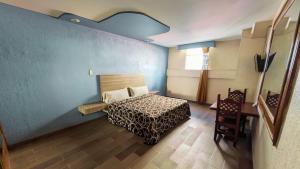 1 dormitorio con cama y pared azul en Hotel Plaza San Juan en Ciudad de México