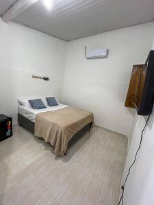 a bedroom with a bed in a white room at Hospedagem na rua da Tartaruga in Búzios