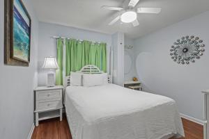 Un dormitorio con una cama blanca y un ventilador de techo. en Driftwood Towers 1G, en Gulf Shores