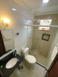a bathroom with a toilet and a sink and a shower at Pousada Dom Fernandes in Cabo Frio