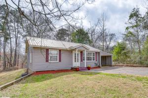 une petite maison blanche avec des parures rouges dans l'établissement Peaceful Tallassee Cottage on 2 Acres!, à Tallassee