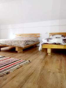 two beds sitting in a room with wooden floors at Casa Pietrosu Rodnei in Borşa