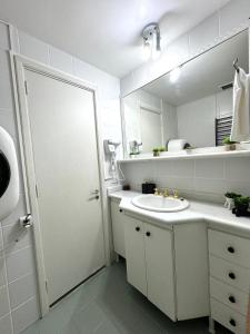 uma casa de banho branca com um lavatório e um espelho em Apartamento Copa Resort HIR 19 no Rio de Janeiro