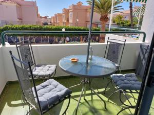 a glass table and chairs on a balcony at APARTAMENTOS SURYCAN in Maspalomas