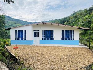 a white and blue house with a mountain in the background at Reserva La Esperanza in Vergara