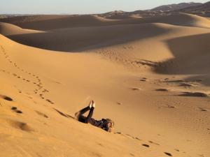 a person laying on the sand in the desert at Luxury Camp Camelhouse in Merzouga