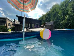 uma piscina com um guarda-chuva e uma bola na água em Upscale Spacious Chalet w Hot Tub Laurentians, QC! em Prévost