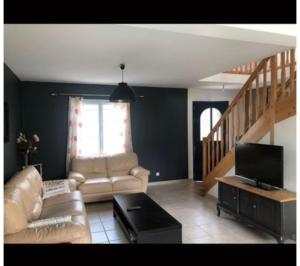 a living room with a couch and a tv at Gîte "Le Millésime 61" in Flavigny