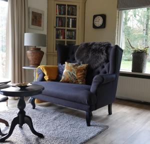 a living room with a blue chair and a table at Hof van Benten in Ermelo