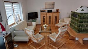 a living room with white chairs and a tv at Chiemsee-Ferienhaus Schlegel in Breitbrunn am Chiemsee