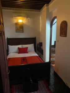 a bedroom with a bed with a red pillow on it at Charmant Ryad à 1mn de BAB BOUJLOUD DAR SERRAJ in Fez