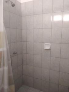 y baño con ducha y pared de azulejos blancos. en HOSPEDAJE PARACAS SUR en Paracas