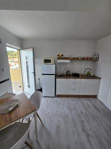 a kitchen with a white refrigerator and a table at Apartmani Alma in Podgora