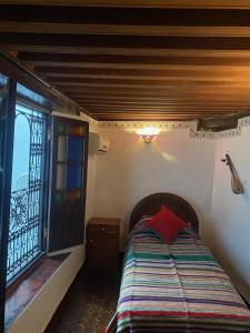 um quarto com uma cama num quarto com uma janela em Charmant Ryad à 1mn de BAB BOUJLOUD DAR SERRAJ em Fez