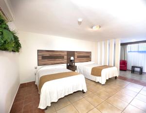 two beds in a room with white walls at Hotel Maria Dolores Rio Verde in Río Verde
