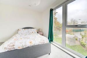 een slaapkamer met een bed en een groot raam bij Beautifully furnished 3-bed apartment near Wembley Stadium in Wealdstone