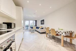 a kitchen and living room with a table and a couch at Beautifully furnished 3-bed apartment near Wembley Stadium in Wealdstone