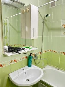 La salle de bains est pourvue d'un lavabo, d'un miroir et d'une baignoire. dans l'établissement Апартаменты 2-х и 1 комнатные, à Taraz