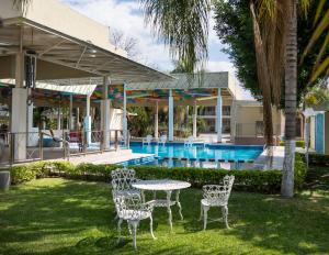 a table and chairs in the grass near a pool at Hotel Maria Dolores Rio Verde in Río Verde