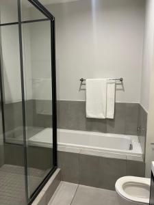 a bathroom with a shower and a tub and a toilet at The Fitz Apartment in Johannesburg