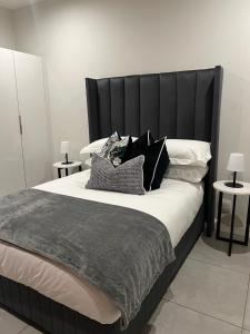 a large bed with a black headboard and pillows at The Fitz Apartment in Johannesburg