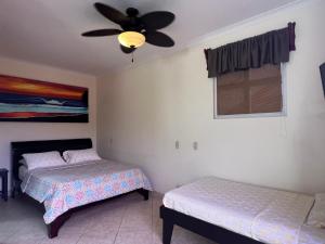1 dormitorio con 2 camas y ventilador de techo en Surf Inn Hermosa, en Playa Hermosa