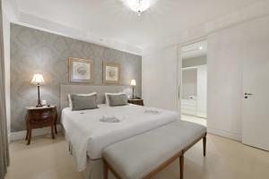 a white bedroom with a large bed and a table at Hotel Mont Blanc Premium in Ribeirão Preto