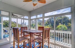 ein Esszimmer mit einem Tisch, Stühlen und Fenstern in der Unterkunft 29 Ocean Point AvantStay Luxe Kitchen Balcony in Isle of Palms