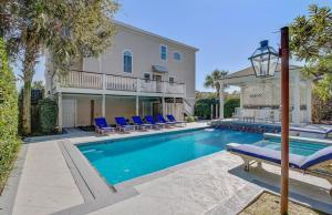 a swimming pool with blue chairs and a house at Endless Summer by AvantStay Across From Beach Ocean Views in Isle of Palms