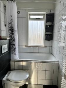 uma casa de banho com uma banheira, um WC e uma janela. em Cozy, central Apartment em Reykjavík