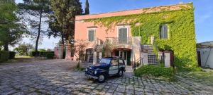 una piccola auto blu parcheggiata di fronte a un edificio di Villa Morea-Relax in piscina a Putignano