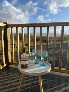 a table with two bottles and glasses on a deck at Hidden Hut - Aros View - Tobermory in Tobermory