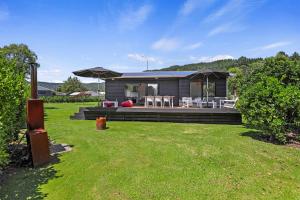 ein Haus mit einer Terrasse mit Stühlen und Sonnenschirmen in der Unterkunft Rad Little Pad in Rotorua