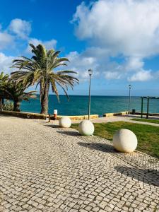 a cobblestone walkway with white balls in front of the ocean at Casa Da Praia in Luz
