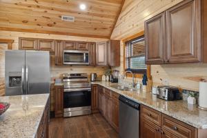 een keuken met houten kasten en roestvrijstalen apparatuur bij Mountain Majesty ~ 28 Person Indoor Pool Cabin in Sevierville