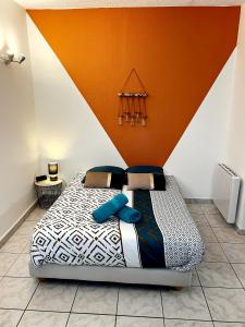 Cama en habitación con pared de color naranja en Studio A au pied des Thermes de Néris-les-Bains en Néris-les-Bains