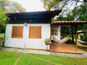 a small white house with a wooden deck at Casa de Campo Pampulha in Belo Horizonte