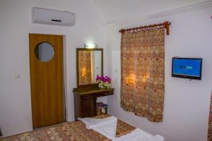 オルデニズにあるSunmed Lodgeのテレビ、鏡、ベッドが備わる客室です。