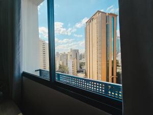 ein Fenster mit Blick auf die Skyline der Stadt in der Unterkunft Apê Metrô Paraíso in São Paulo