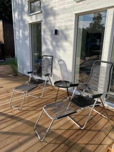 3 Stühle auf einer Terrasse neben einem Haus in der Unterkunft Hus med pool, badtunna och 450 m till havet in Beddinge Strand