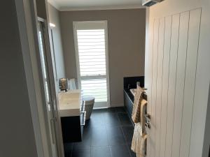 a bathroom with a sink and a toilet and a window at Pegasus Amberley, Entire Studio in Waikuku