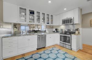 a kitchen with white cabinets and a blue rug at 211 Seascape by AvantStay Oceanfront View Pool in Isle of Palms