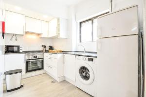 Una cocina blanca con lavadora y secadora. en Apartamento no Centro de Albufeira com Piscina, en Albufeira
