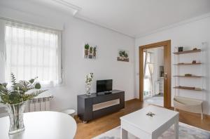 a white living room with a tv and a table at Rio Nalón in Pravia