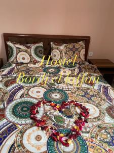 a bed with a colorful comforter with a word worldforth on it at HOSTEL BORDJ ELKIFFAN in Fort de lʼEau