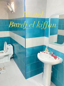 a blue and white bathroom with a sink and a toilet at HOSTEL BORDJ ELKIFFAN in Fort de lʼEau