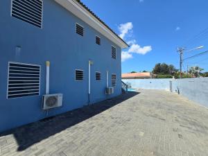 un edificio azul con una acera de ladrillo al lado en Cattleya Apartments Curacao, en Willemstad